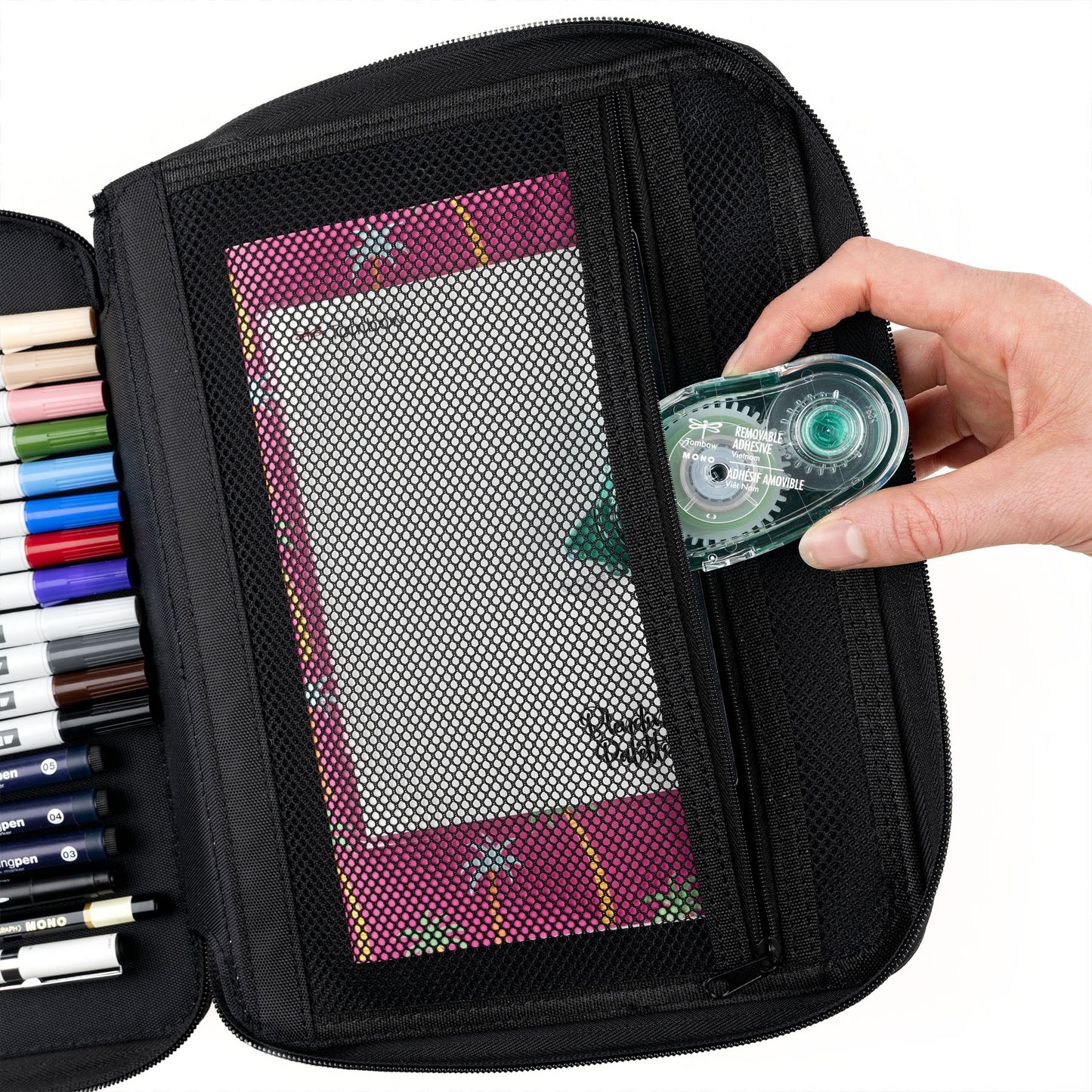 Black pencil case with colorful pens and a hand holding a green tape dispenser.
