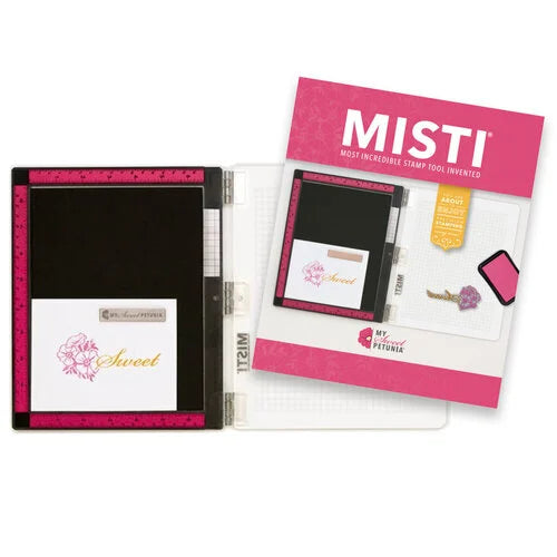 MISTI stamp tool set shown open on a white background, with a pink-and-white instruction card, a black stamp holder, and sample stamped cards visible inside.